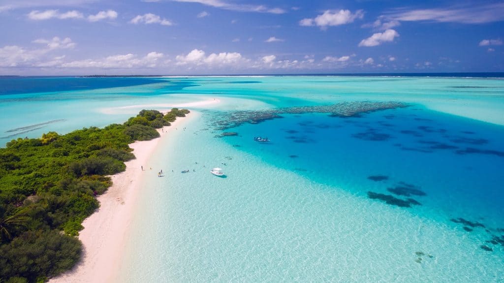 Stunning photo of a clear blue sea with a beach stretching out into the distance.