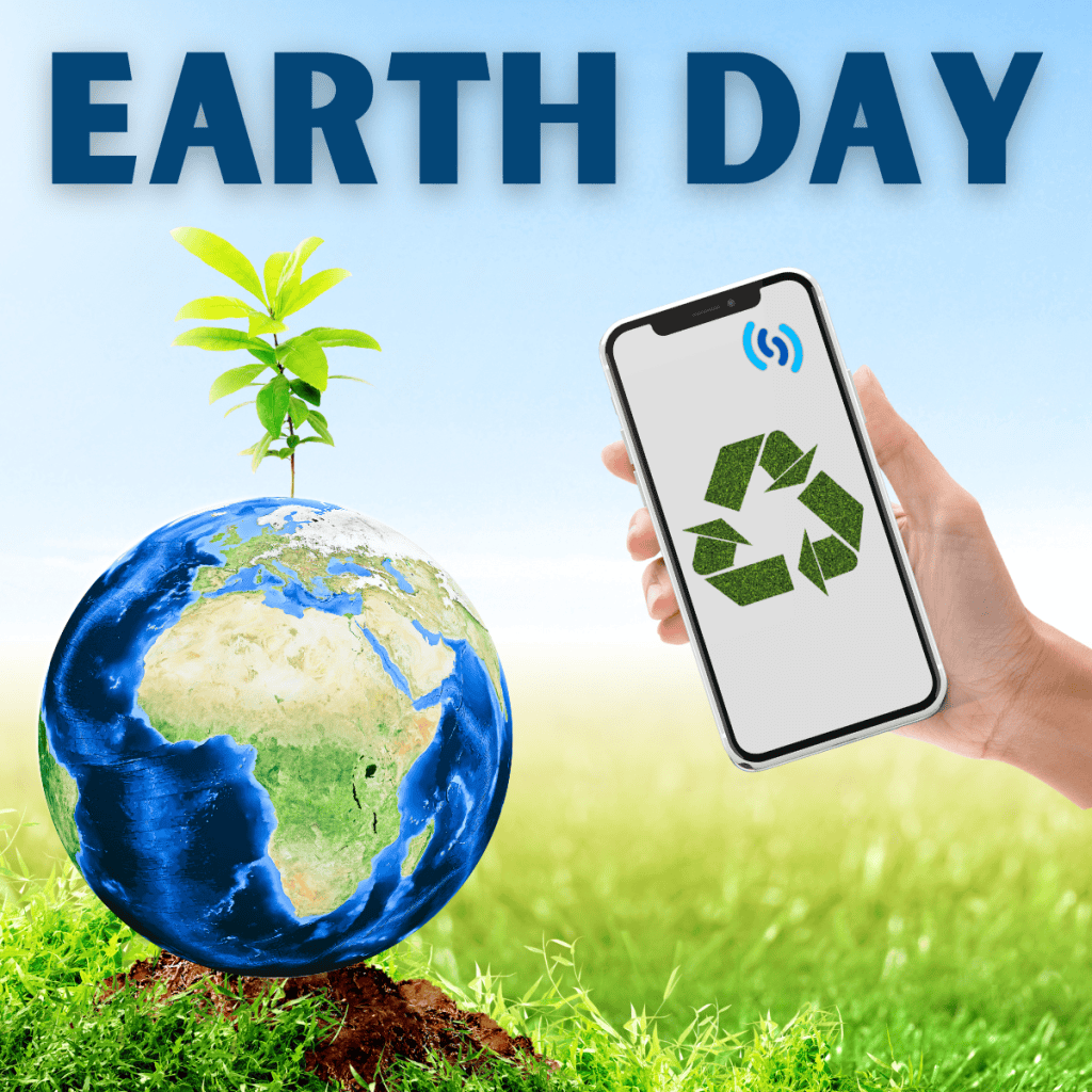 Hi there this image depicts how you can be more environmentally friendly with your mobile phone in celebration of Earth Day. The image has a blue/green theme and across the top in dark blue letters it says Earth Day. To the left is a dark blue earth globe sat on a mound of earth, and sprouting out of the top of the globe is a small green seedling. To the right is a hand holding a mobile phone with the generic logo for recycling (3 green arrows) on the screen. The background is grassy with a pale blue sky.